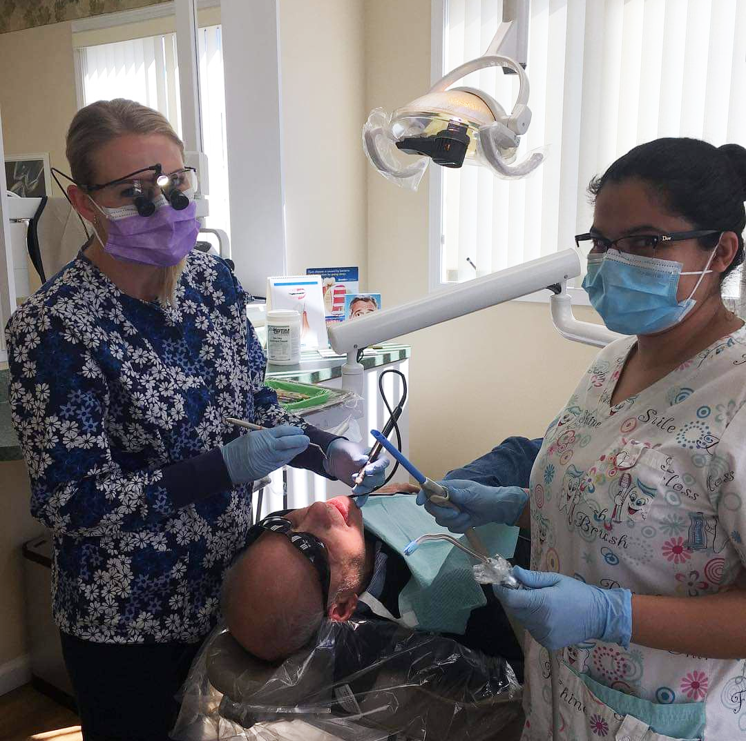 Jannette and her assistant give a cleaning to a patient with a disability